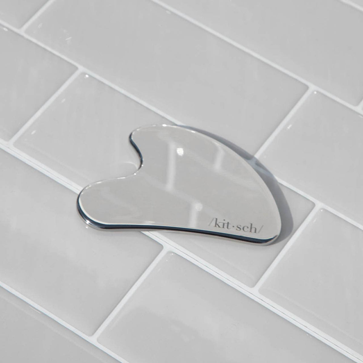 DIY Skincare Lab™ stainless steel gua sha tool for facial massage and lymphatic drainage on a tiled surface