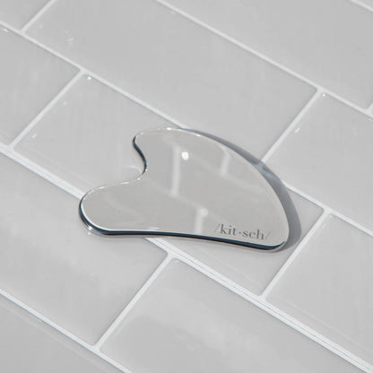 DIY Skincare Lab™ stainless steel gua sha tool for facial massage and lymphatic drainage on a tiled surface